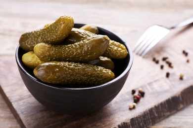 Photo of Bowl with pickled cucumbers on wooden table, closeup