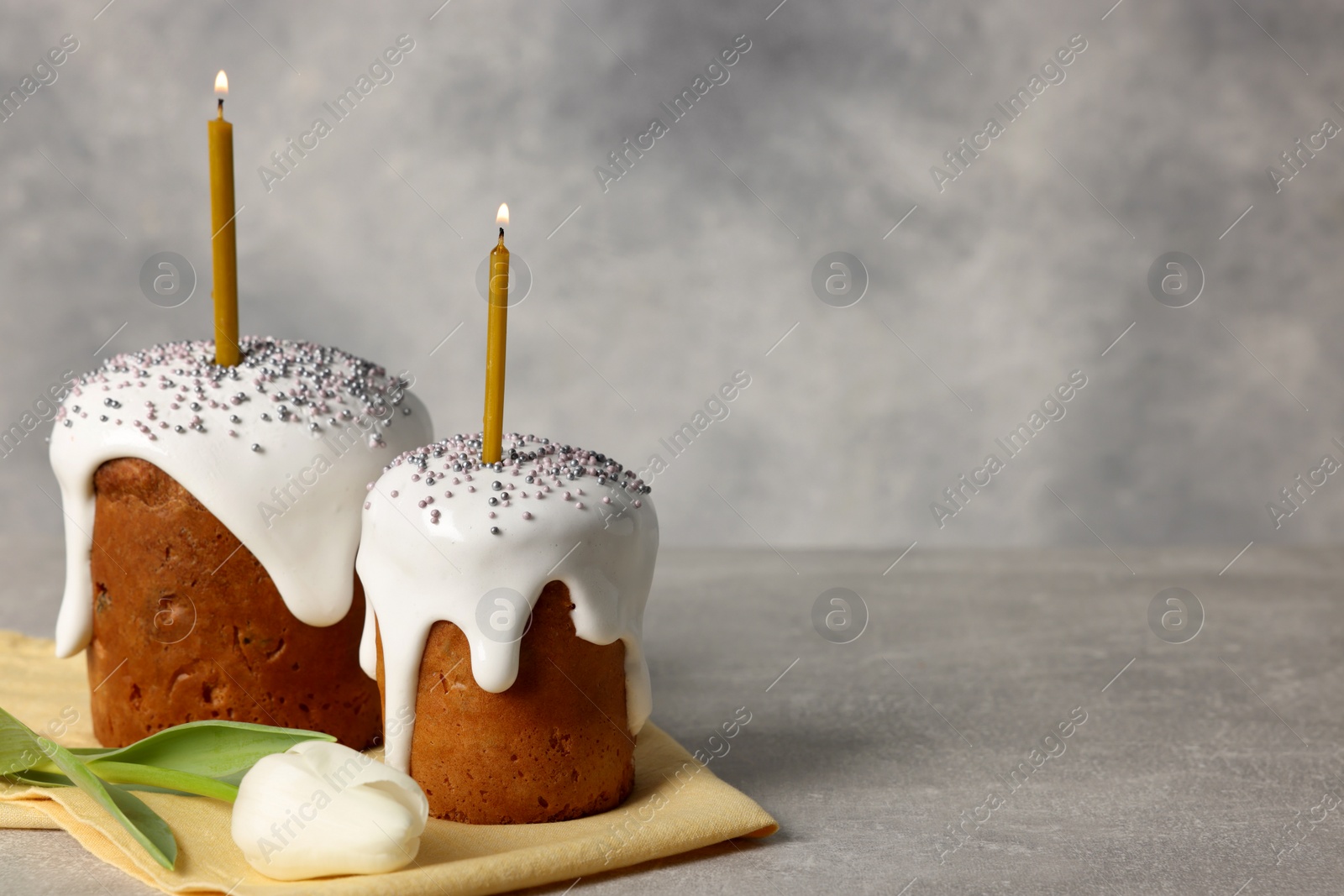 Photo of Tasty Easter cakes and tulip flower on grey table. Space for text