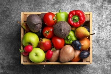 Photo of Wooden crate full of different vegetables and fruits on grey table, top view. Harvesting time