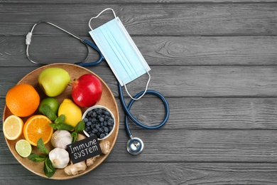 Photo of Card with phrase Immunity System, medical items and fresh products on grey wooden table, flat lay. Space for text