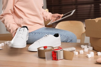 Photo of Shoes seller working with tablet in office, closeup. Online store