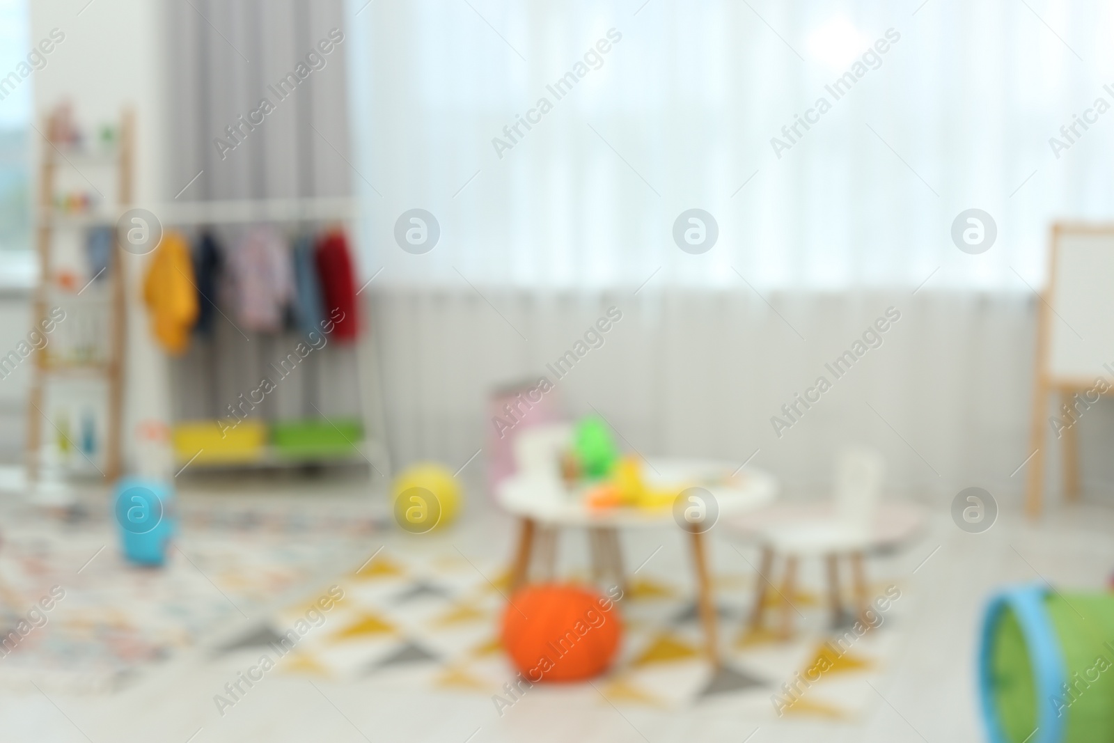 Photo of Blurred view of child`s playroom with different toys and furniture. Stylish kindergarten interior