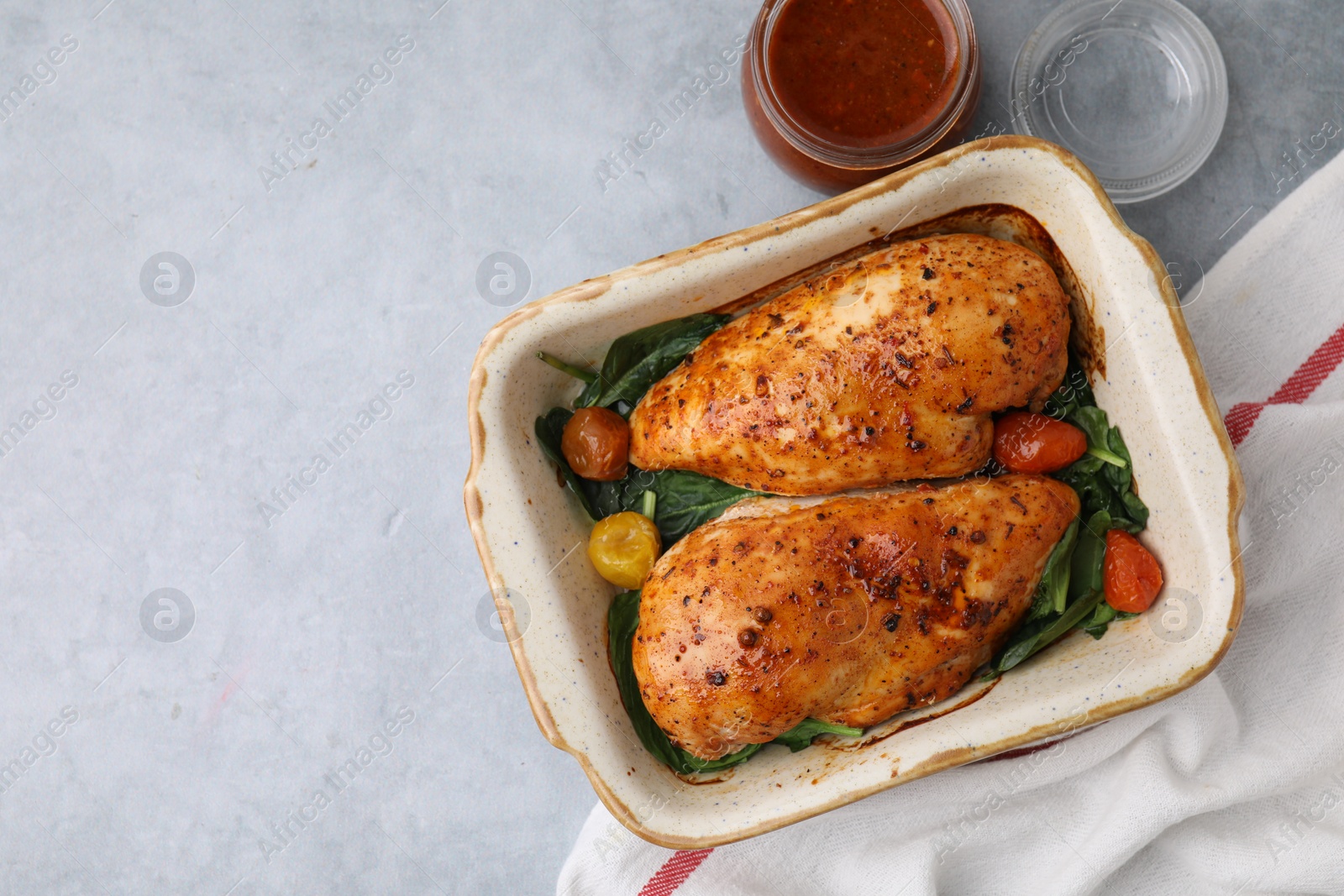 Photo of Baked chicken fillets with vegetables and marinade on grey table, top view. Space for text