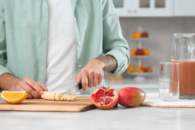 Photo of Man preparing ingredients for tasty smoothie at white marble table in kitchen, closeup