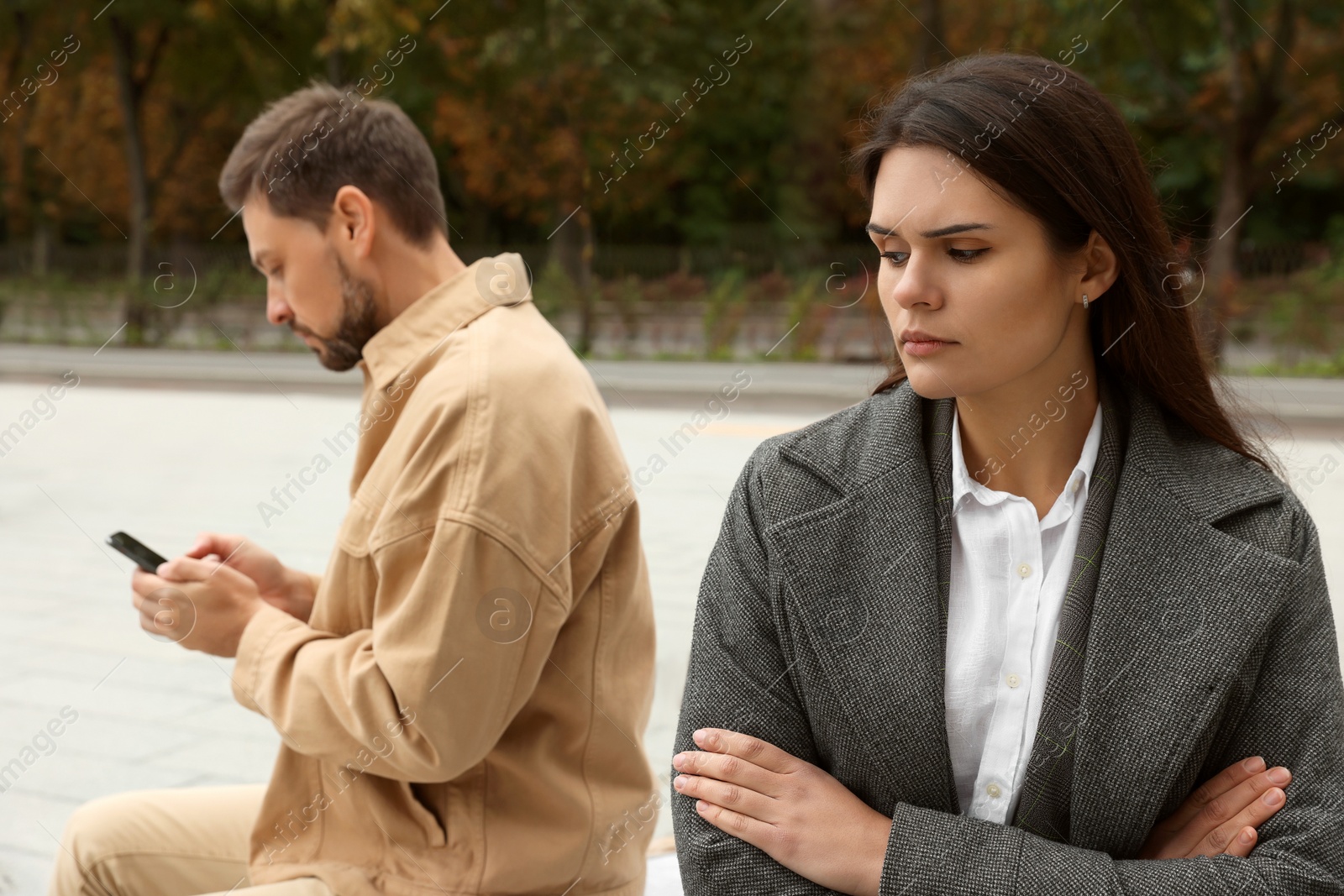 Photo of Upset arguing couple sitting on bench in park. Relationship problems