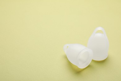 Photo of Menstrual cups on light green background. Space for text