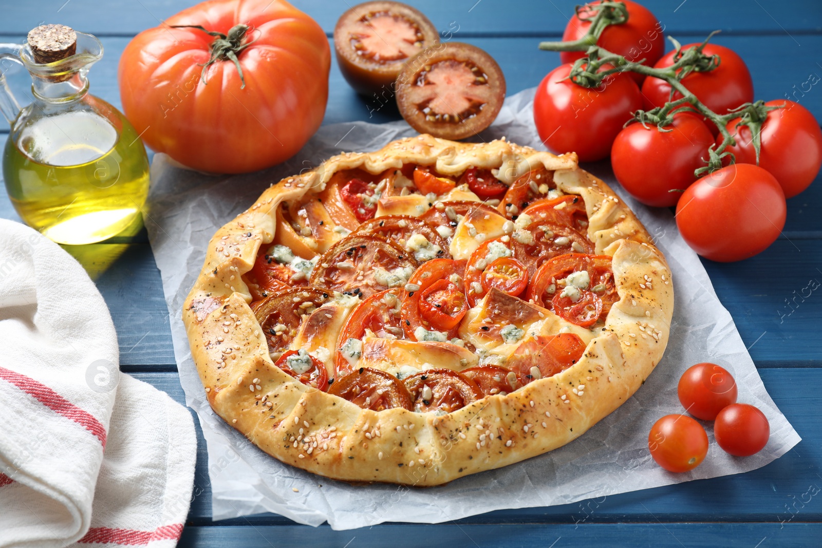 Photo of Tasty galette with tomato and cheese (Caprese galette) on blue wooden table, closeup