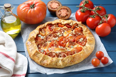 Tasty galette with tomato and cheese (Caprese galette) on blue wooden table, closeup