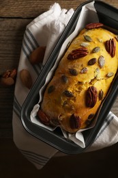 Delicious pumpkin bread with pecan nuts on wooden table, top view