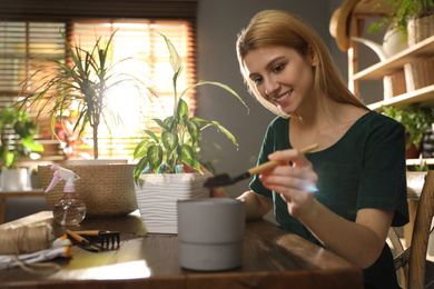 Young woman taking care of plants at home. Engaging hobby