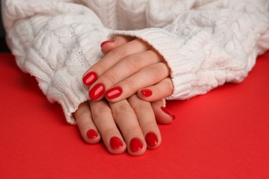 Photo of Woman with gel polish on nails at red table, closeup