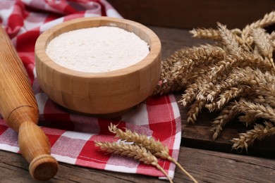 Photo of Ears of wheat and flour on wooden table