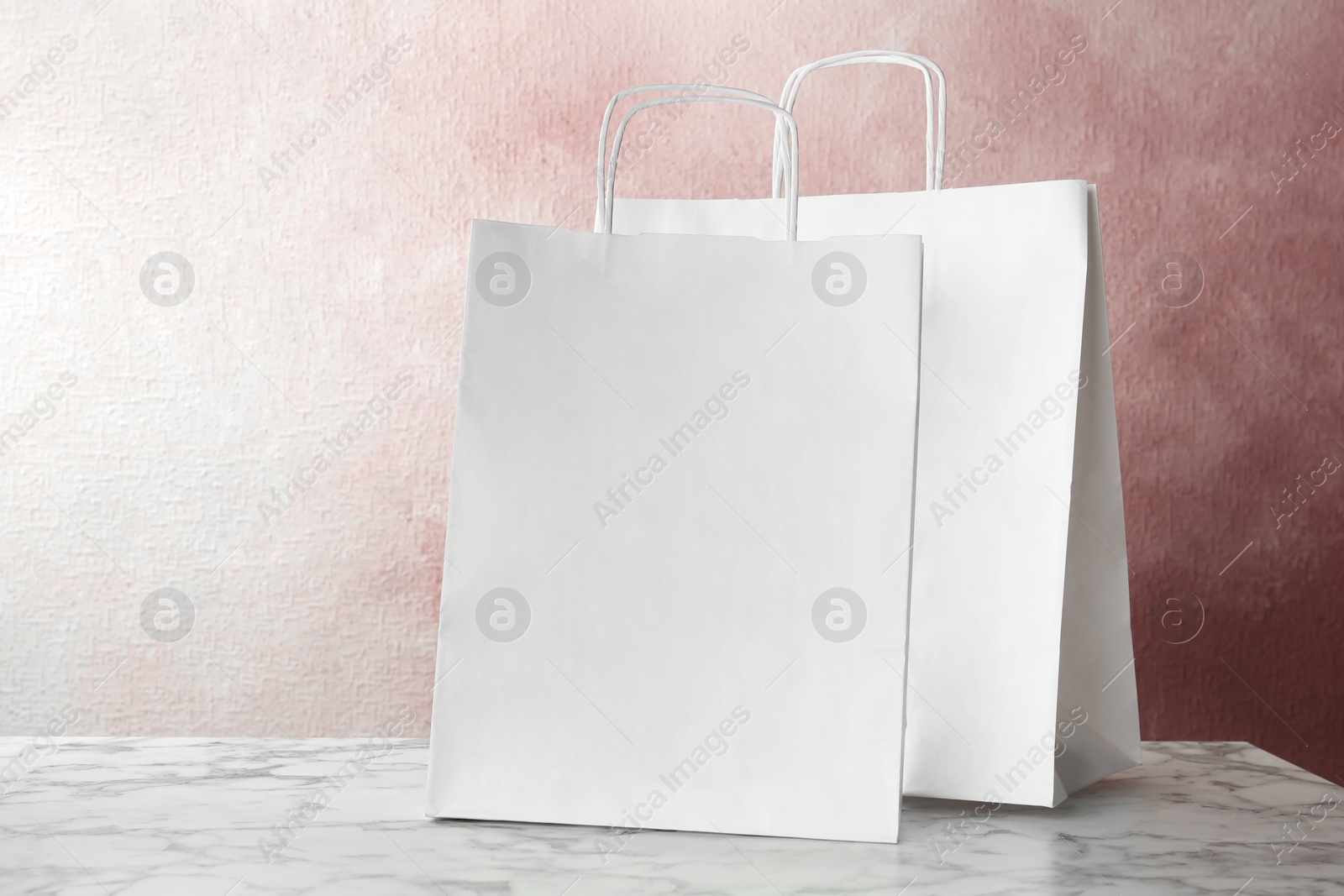 Photo of Mockup of paper shopping bags on table against color background