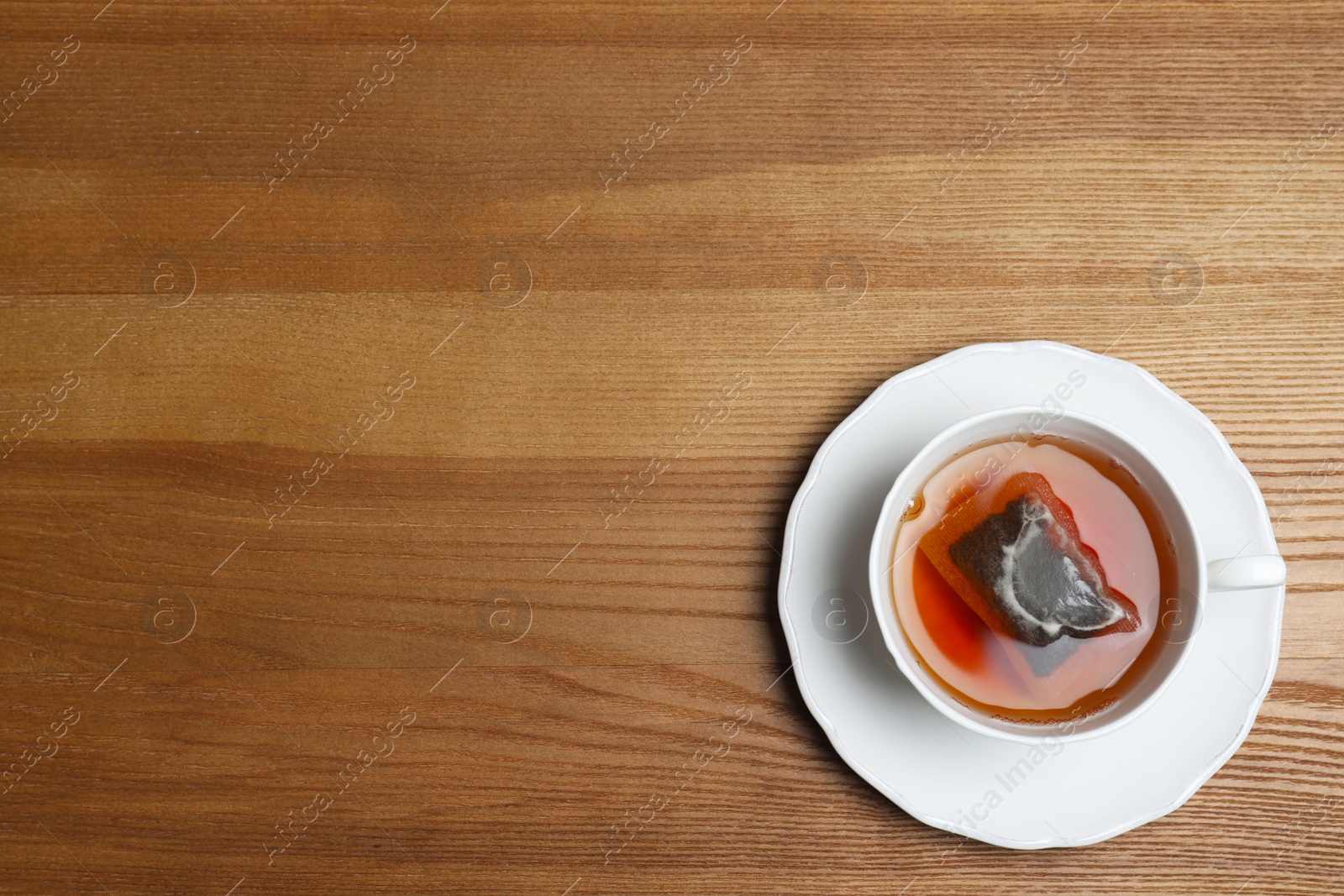 Photo of Cup of hot fresh tea on wooden background, top view. Space for text