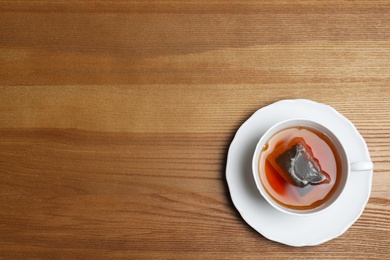 Photo of Cup of hot fresh tea on wooden background, top view. Space for text