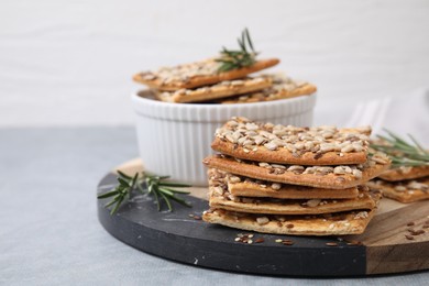 Photo of Cereal crackers with flax, sunflower, sesame seeds and rosemary on grey table, closeup
