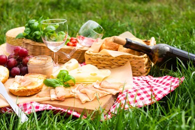 Photo of Picnic blanket with wine and food on green grass