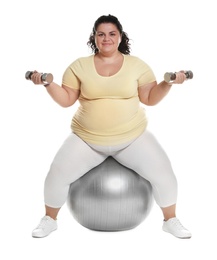 Overweight woman doing exercise on fit ball with dumbbells against white background