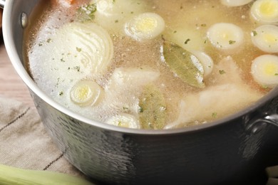 Pot with tasty bouillon on table, closeup