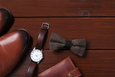 Photo of Stylish brown bow tie, shoes, wristwatch and wallet on wooden background, flat lay. Space for text