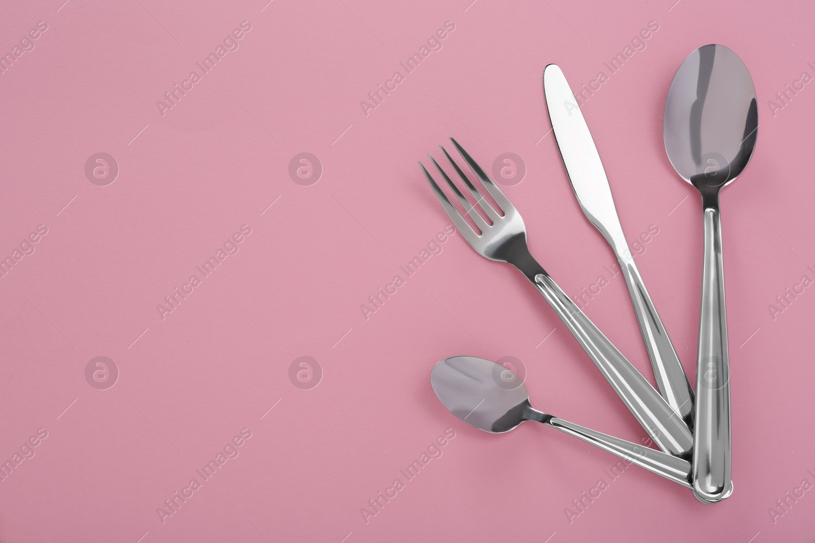 Photo of Stylish cutlery set on pink background, flat lay. Space for text