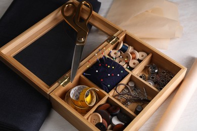 Set of sewing supplies and accessories in wooden organizer on white table