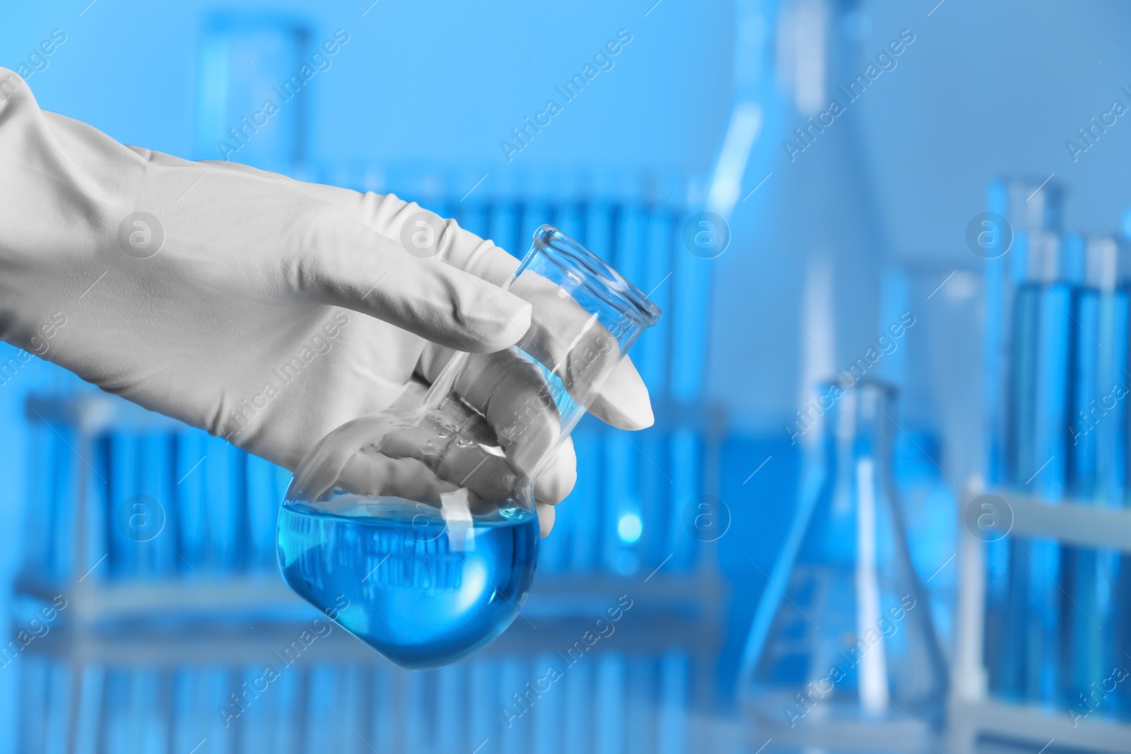 Photo of Scientist holding test flask with sample in laboratory. Chemical analysis