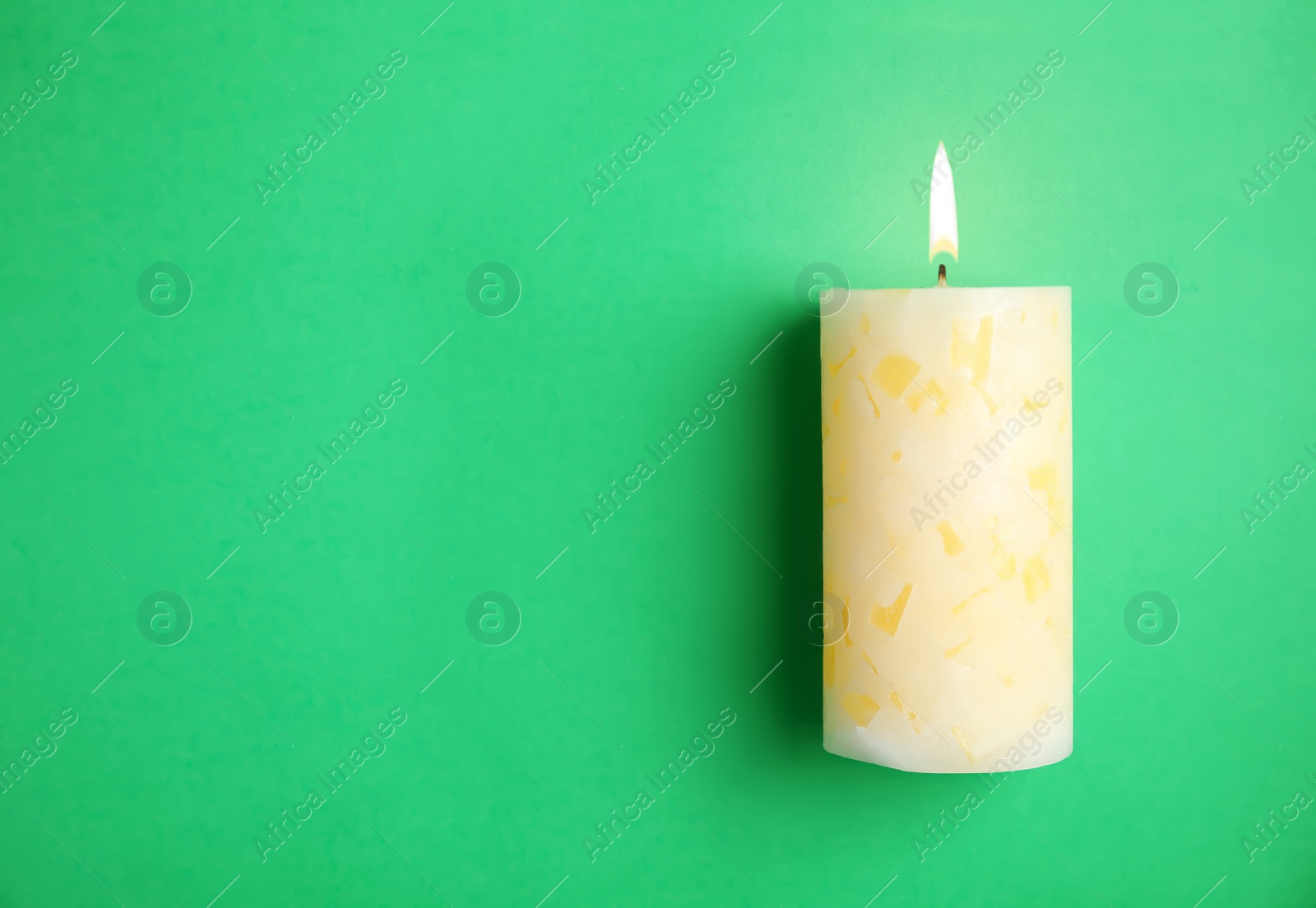 Photo of Alight wax candle and space for text on color background