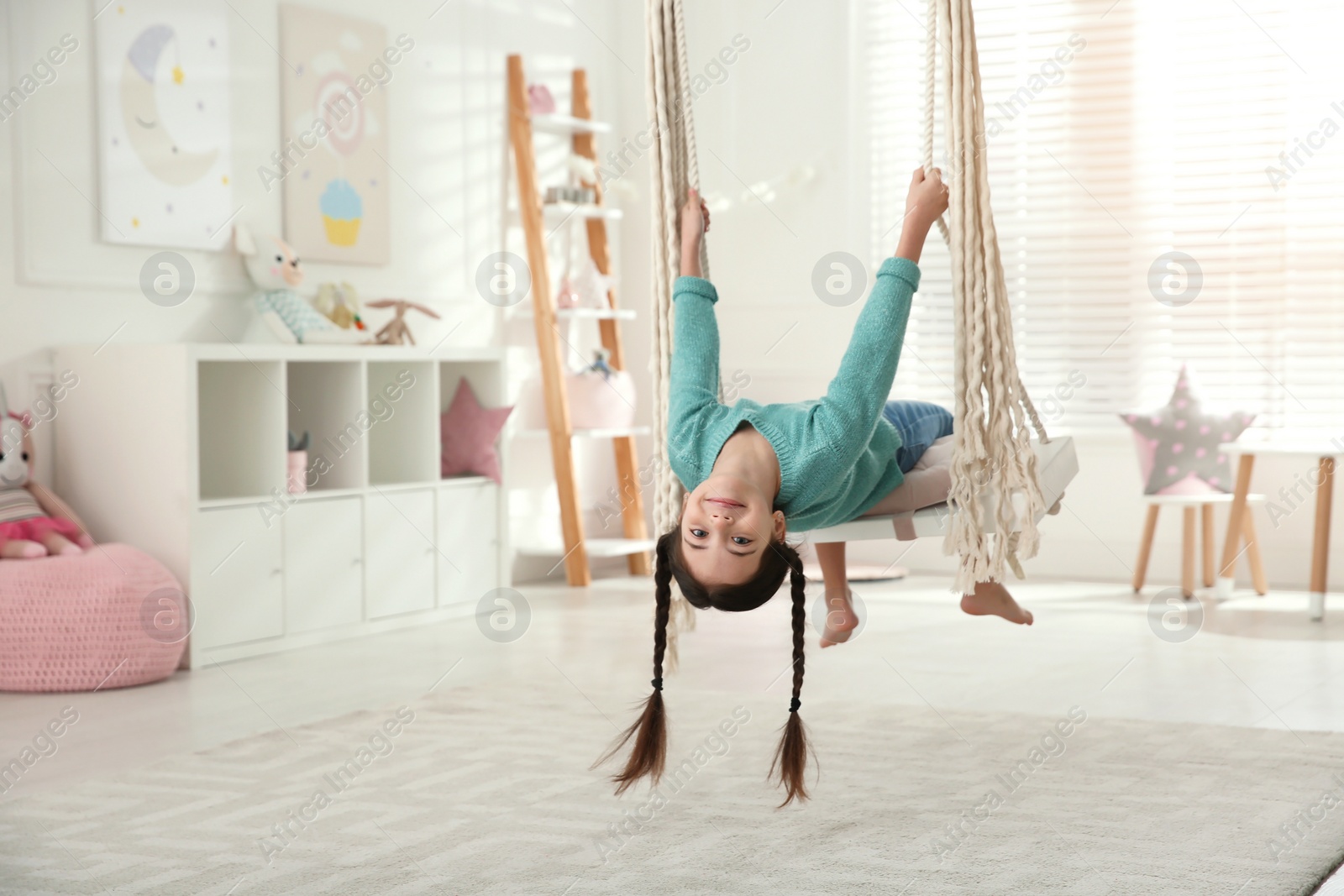 Photo of Cute little girl playing on swing at home