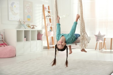 Photo of Cute little girl playing on swing at home