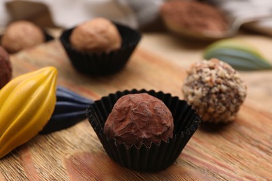 Different tasty chocolate candies on wooden board, closeup