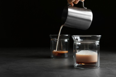 Pouring milk into glass on grey table, space for text. Preparing aromatic coffee