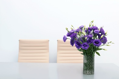 Beautiful bouquet in vase on gray table against color background. Stylish interior