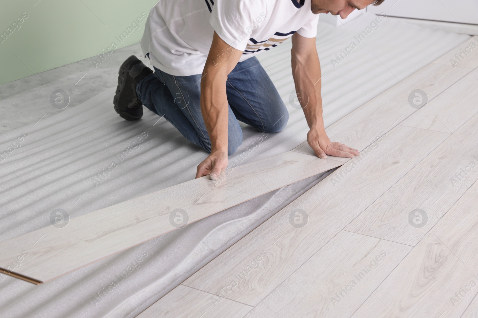 Photo of Man installing new laminate flooring indoors, closeup