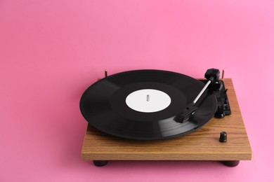 Turntable with vinyl record on pink background. Space for text