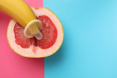 Banana with condom and half of grapefruit on color background, top view and space for text. Safe sex concept