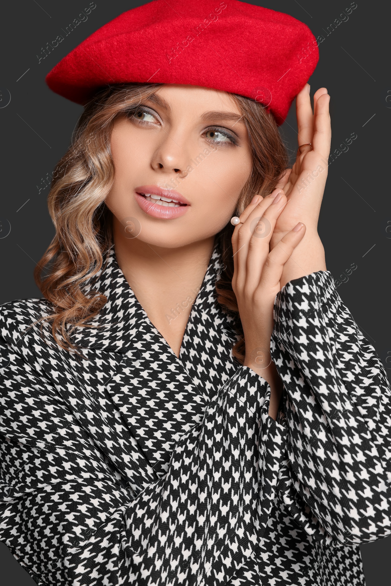 Photo of Young woman with beautiful makeup in red beret against black background