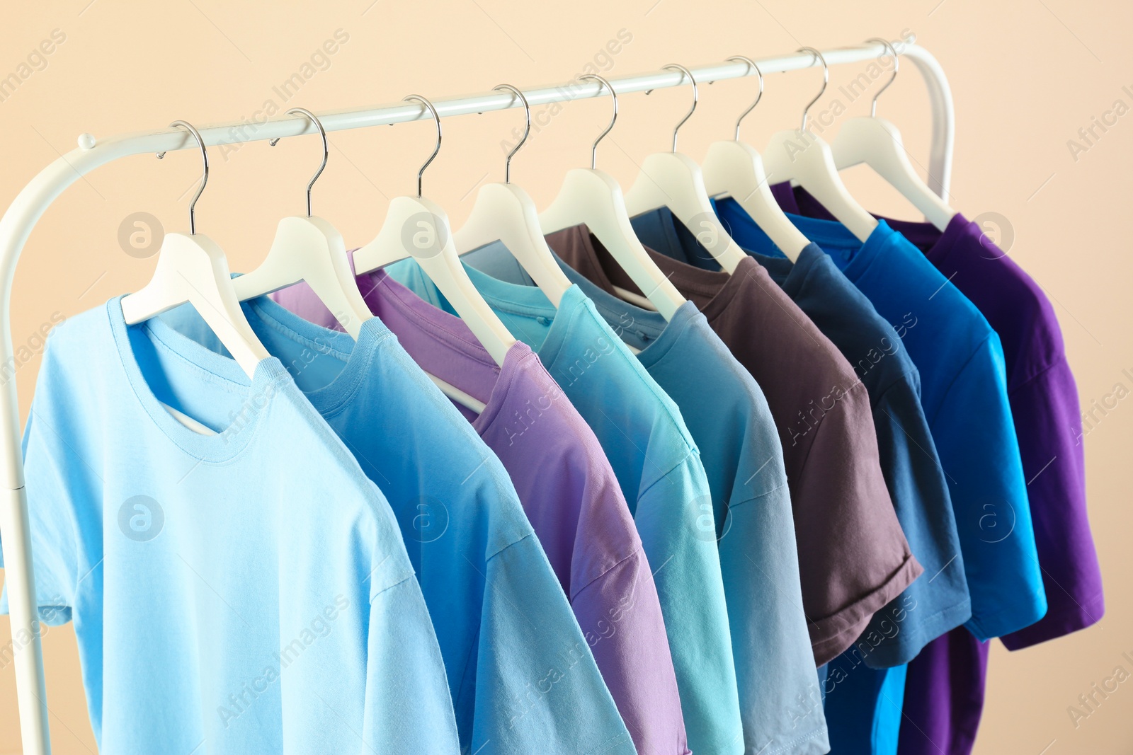 Photo of Men's clothes hanging on wardrobe rack against light background