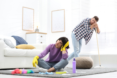 Photo of Lazy couple procrastinating while cleaning at home