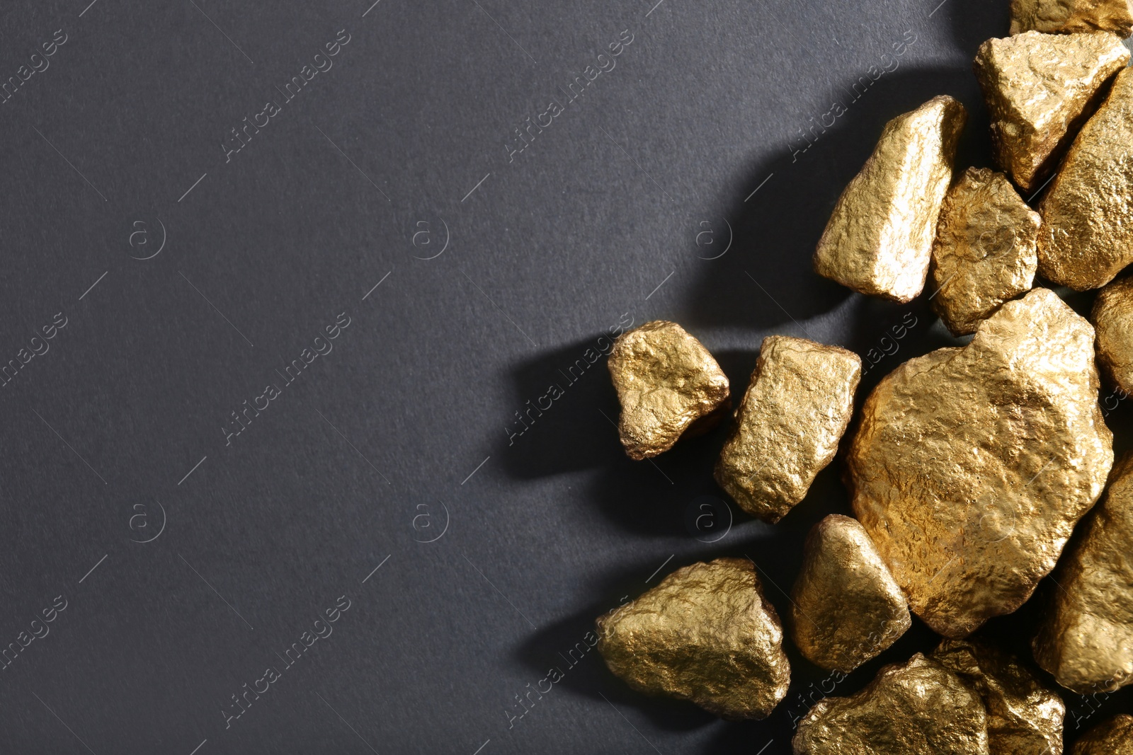 Photo of Pile of gold nuggets on dark background, flat lay with space for text