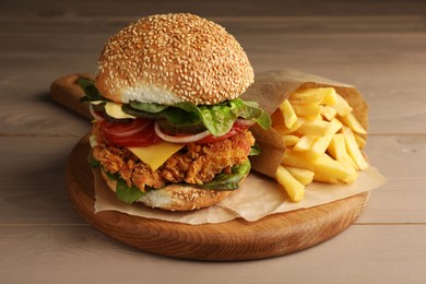 Delicious burger with crispy chicken patty and french fries on wooden table