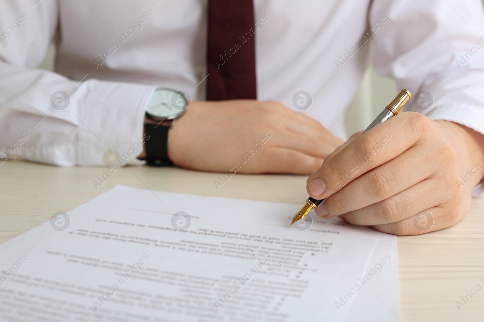 Photo of Notary signing document at wooden table, closeup