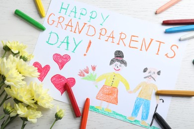 Photo of Beautiful drawing with phrase Happy Grandparents Day on white table, flat lay
