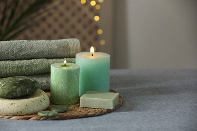 Spa composition. Burning candles, stones, soap and towels on soft grey surface, space for text