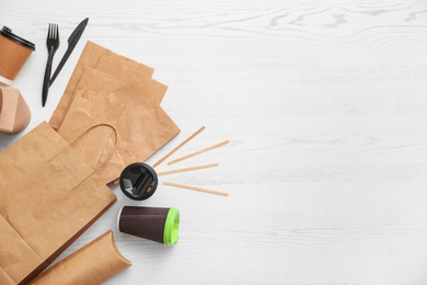 Flat lay composition with paper bags and different takeaway items on wooden background. Space for design
