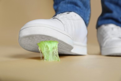 Photo of Person stepping into chewing gum on light brown background, closeup