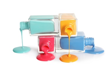 Photo of Spilled different nail polishes with bottles on white background