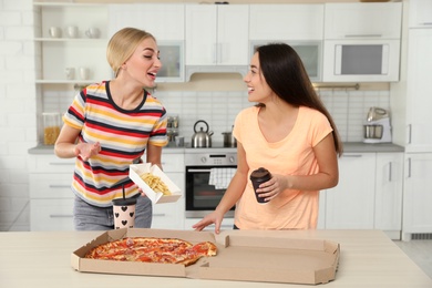 Young women with tasty food laughing in kitchen