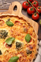 Delicious homemade vegetable quiche and tomatoes on wooden table, flat lay