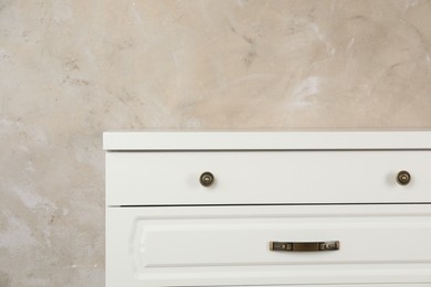 Photo of Modern chest of drawers near beige wall